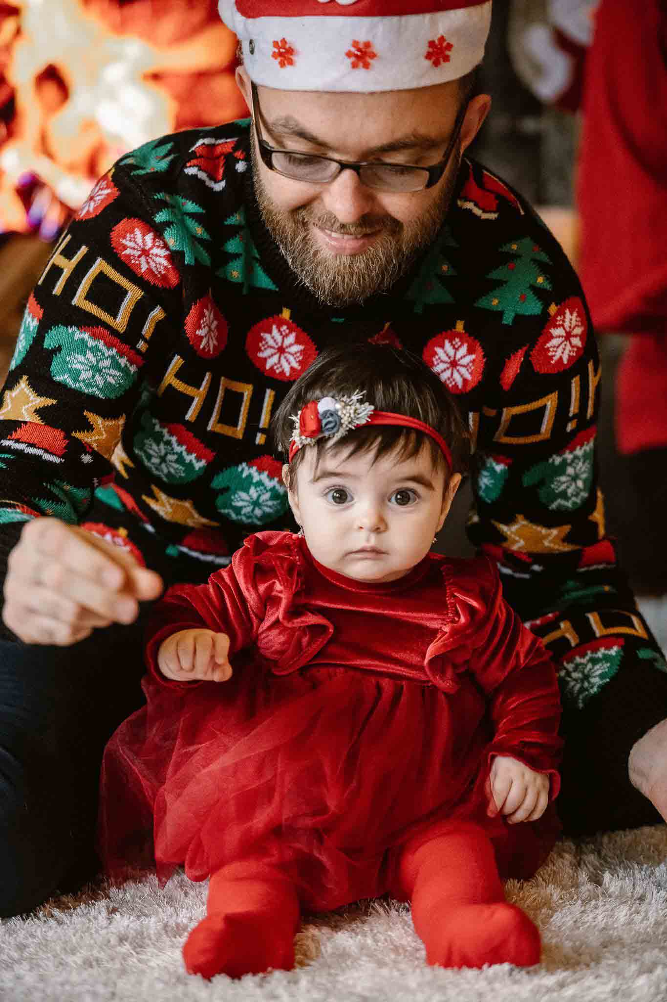 Tată cu bebeluș îmbrăcat în roșu la ședința foto de Crăciun