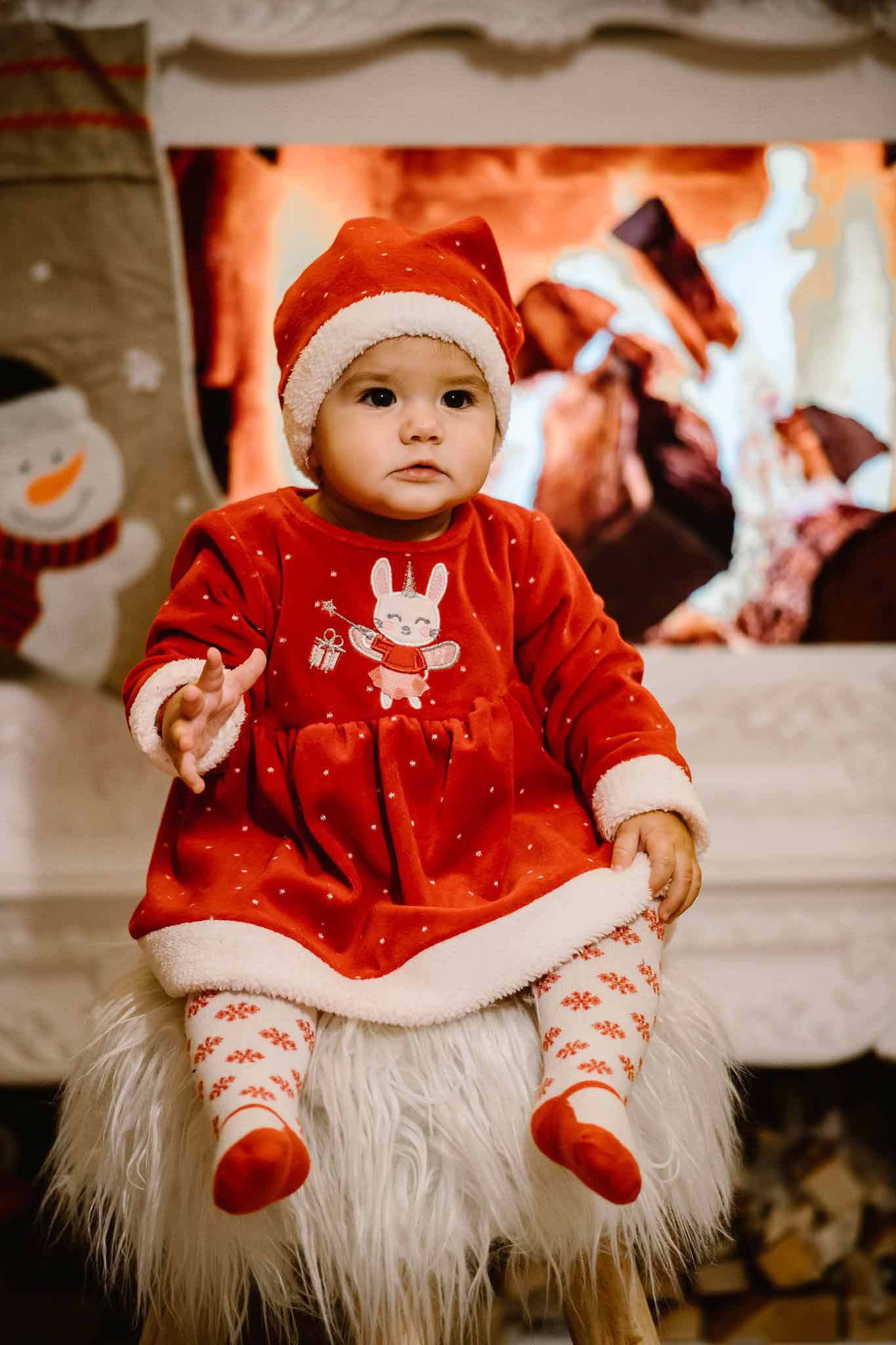 Portret de Crăciun cu personaj așezat pe un taburet pufos, lângă brad